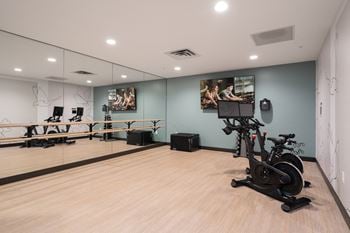 Spin or yoga studio with two workout cycles in right corner and large wall of mirrors on the left.